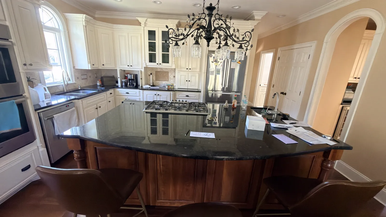 Before: a traditional cream kitchen with a dark granite curved island awaiting renovation