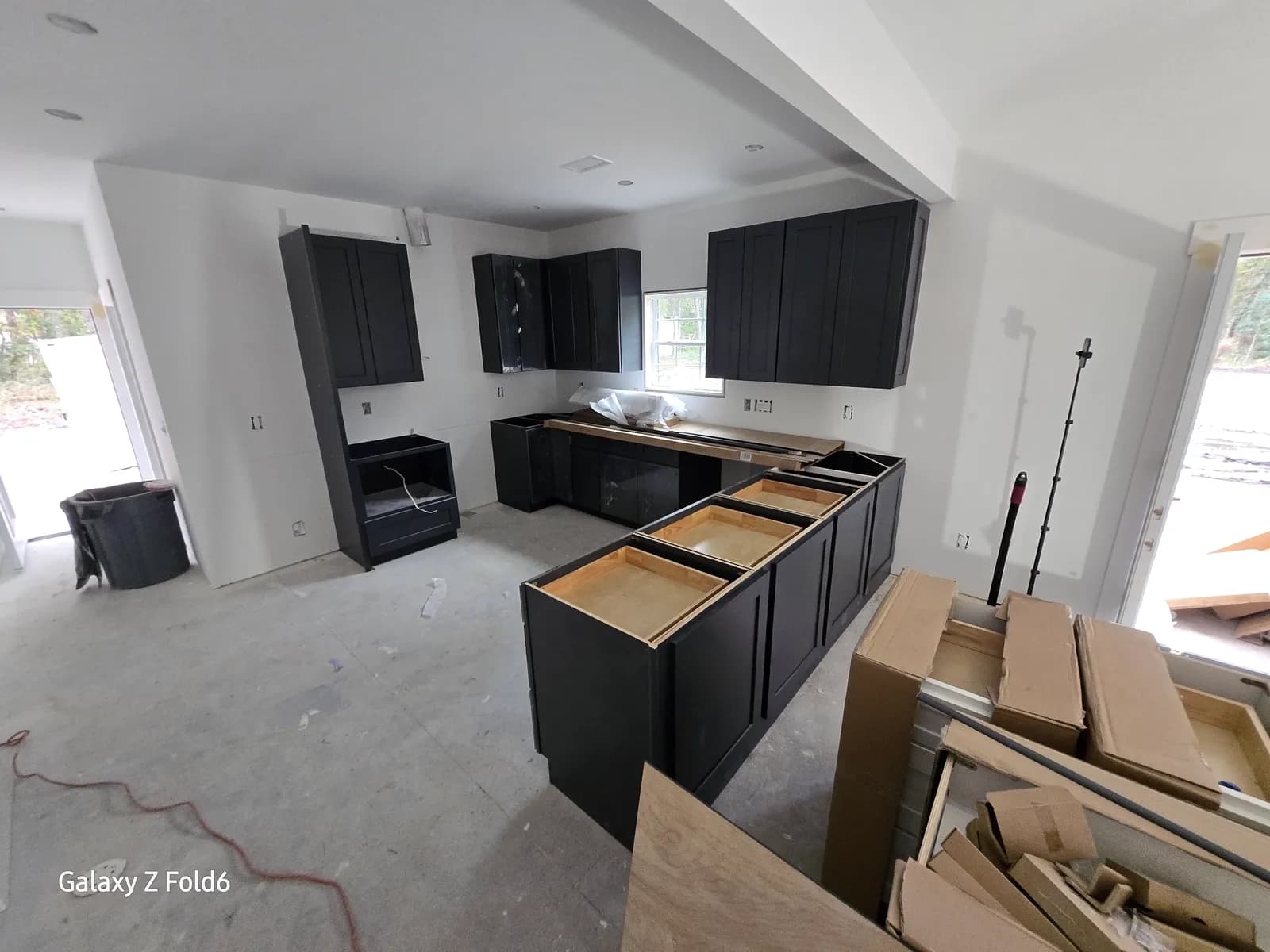 Charcoal cabinetry being installed in a new build before countertops are templated