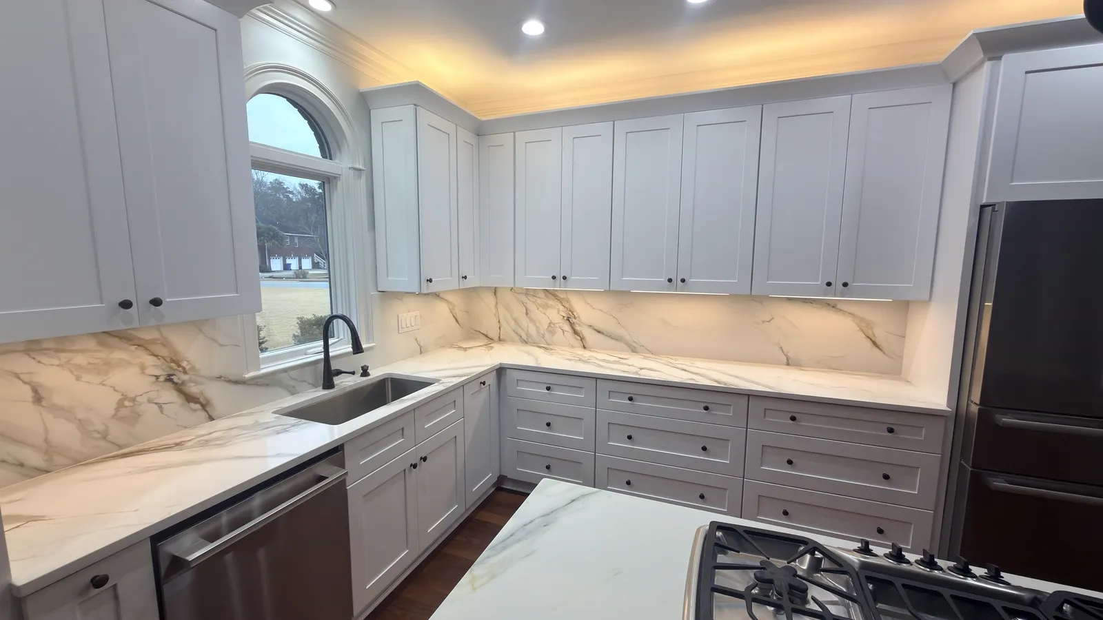 Grey and white kitchen with a book-matched marble backsplash and gas cooktop