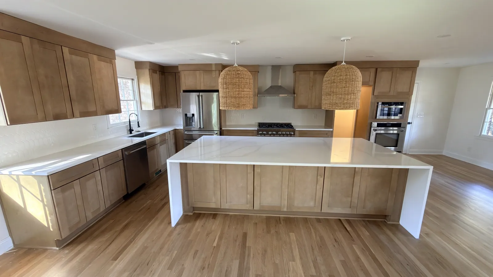 Natural stained oak kitchen with a large waterfall quartz island and rattan pendants