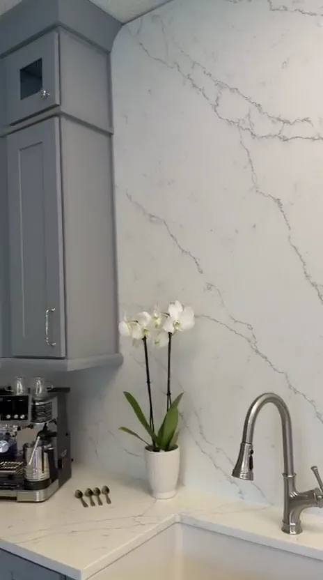 White quartz slab backsplash above a farmhouse sink in the showroom